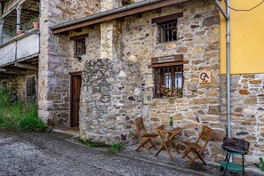 Un edificio de piedra con un letrero que dice 'La Casina del Fornu'. Hay sillas de madera y una pequeña mesa afuera.