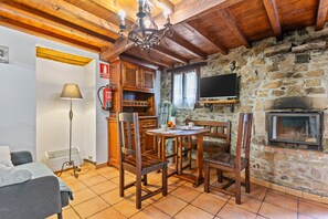 A cozy room with a stone wall, wooden furniture, a fireplace, and a television.
