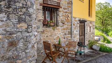 A stone building with a wooden table and chairs, a window with flowers, and a sign reading 'La Casina del Fornu.'