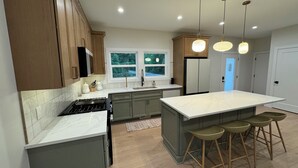 Una cocina moderna con una isla grande, taburetes de bar e iluminación colgante.