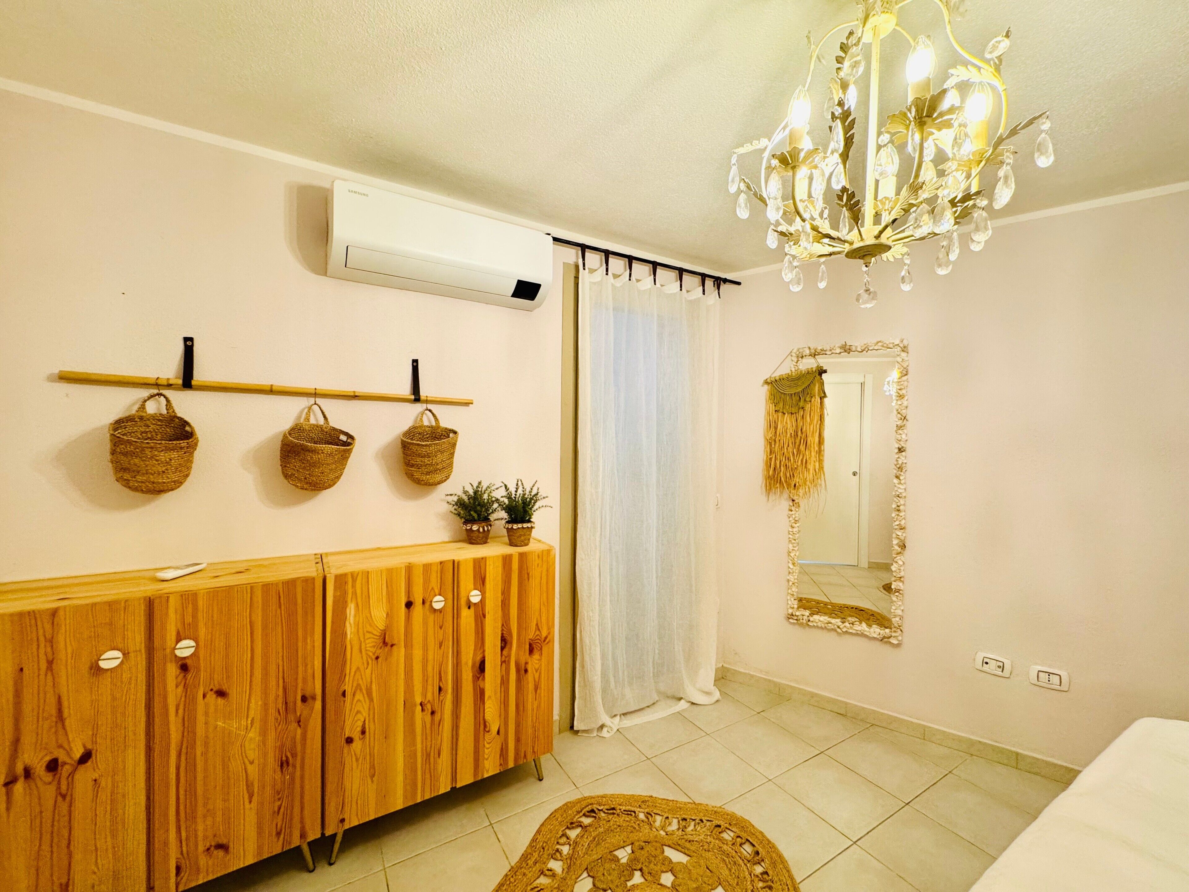 Une pièce avec un meuble en bois, des paniers fixés au mur, un miroir et un lustre.