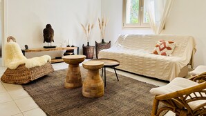A room with a white sofa, a fluffy chair, a wooden table, and a wicker chair. - Holiday Home 'Casa Guilia' with Private Terrace, Wi-Fi and Air Conditioning (Valledoria SS)
