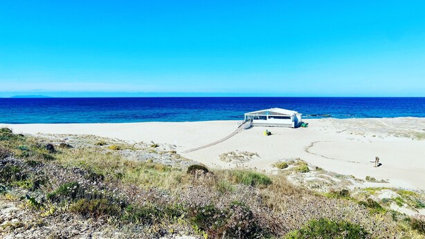 A beachside building with a clear view of the ocean, a sandy path leading to it, and sparse vegetation in the foreground. - Holiday Home 'Casa Guilia' with Private Terrace, Wi-Fi and Air Conditioning (Valledoria SS)