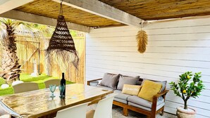 A patio with a wooden table, white chairs, a sofa with cushions, a hanging light fixture, and a potted plant. - Holiday Home 'Casa Guilia' with Private Terrace, Wi-Fi and Air Conditioning (Valledoria SS)