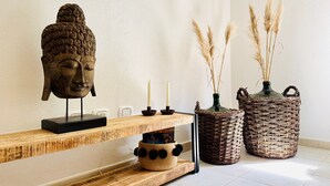 A wooden shelf with a Buddha head sculpture, candles, a woven basket, and a vase with pampas grass. - Holiday Home 'Casa Guilia' with Private Terrace, Wi-Fi and Air Conditioning (Valledoria SS)