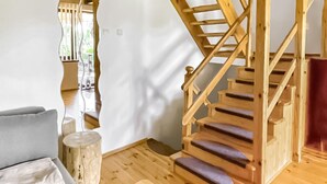 Un escalier en bois avec une rampe et un canapé gris dans une pièce au plancher en bois et aux murs blancs.