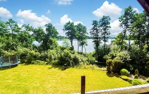 A view of a lake surrounded by trees and a grassy area with a trampoline.