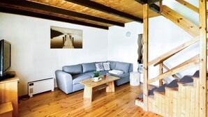 Un salon chaleureux avec un plancher en bois, un canapé gris, une table basse en bois et un tableau accroché au mur.