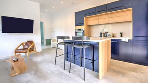 Eine moderne Küche mit Barhocker, einem Flachbildfernseher und einer Wand mit Holzpaneelen.