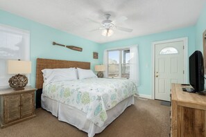 Una camera da letto con un letto, due comodini, una ventola a soffitto, una porta e una televisione.