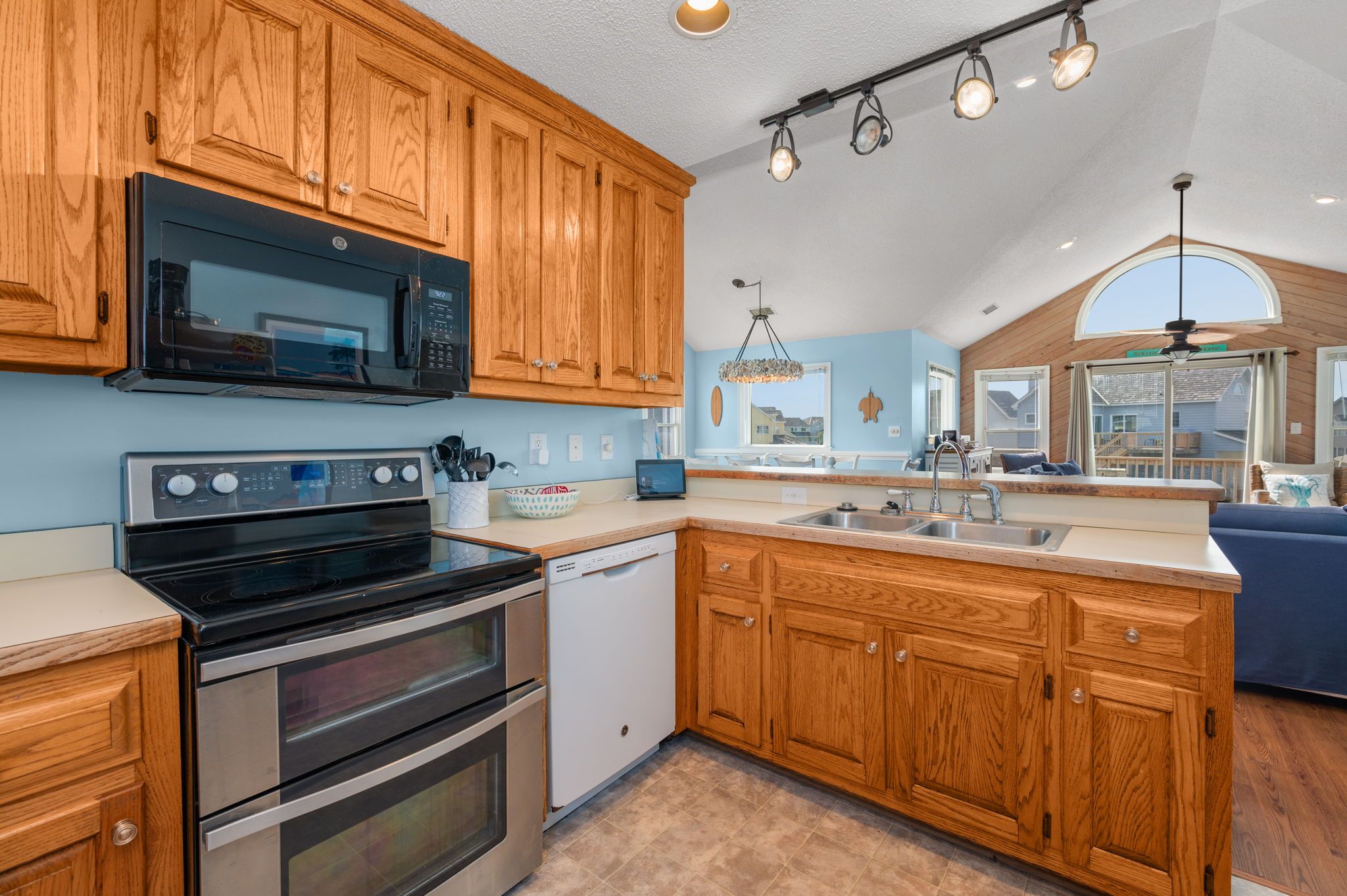 A kitchen with wooden cabinets, stainless steel appliances, a dishwasher, and a large island with a sink.