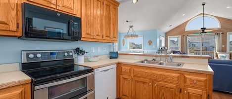A kitchen with wooden cabinets, stainless steel appliances, a dishwasher, and a large island with a sink.