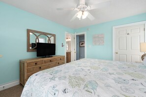 A bedroom with a bed, a dresser, a television, a ceiling fan, and a door. - Wanderer's Rest: Oceanside, Private Pool, Hot Tub, Close to Beach! (Nags Head)