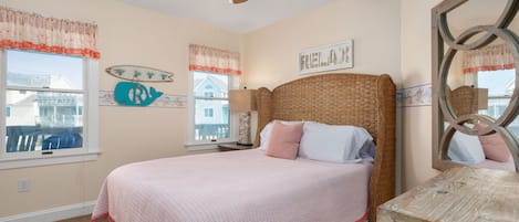 Quarto com cama, ventoinha no teto, janela com vista e um quadro com a inscrição 'FRIENDS'.