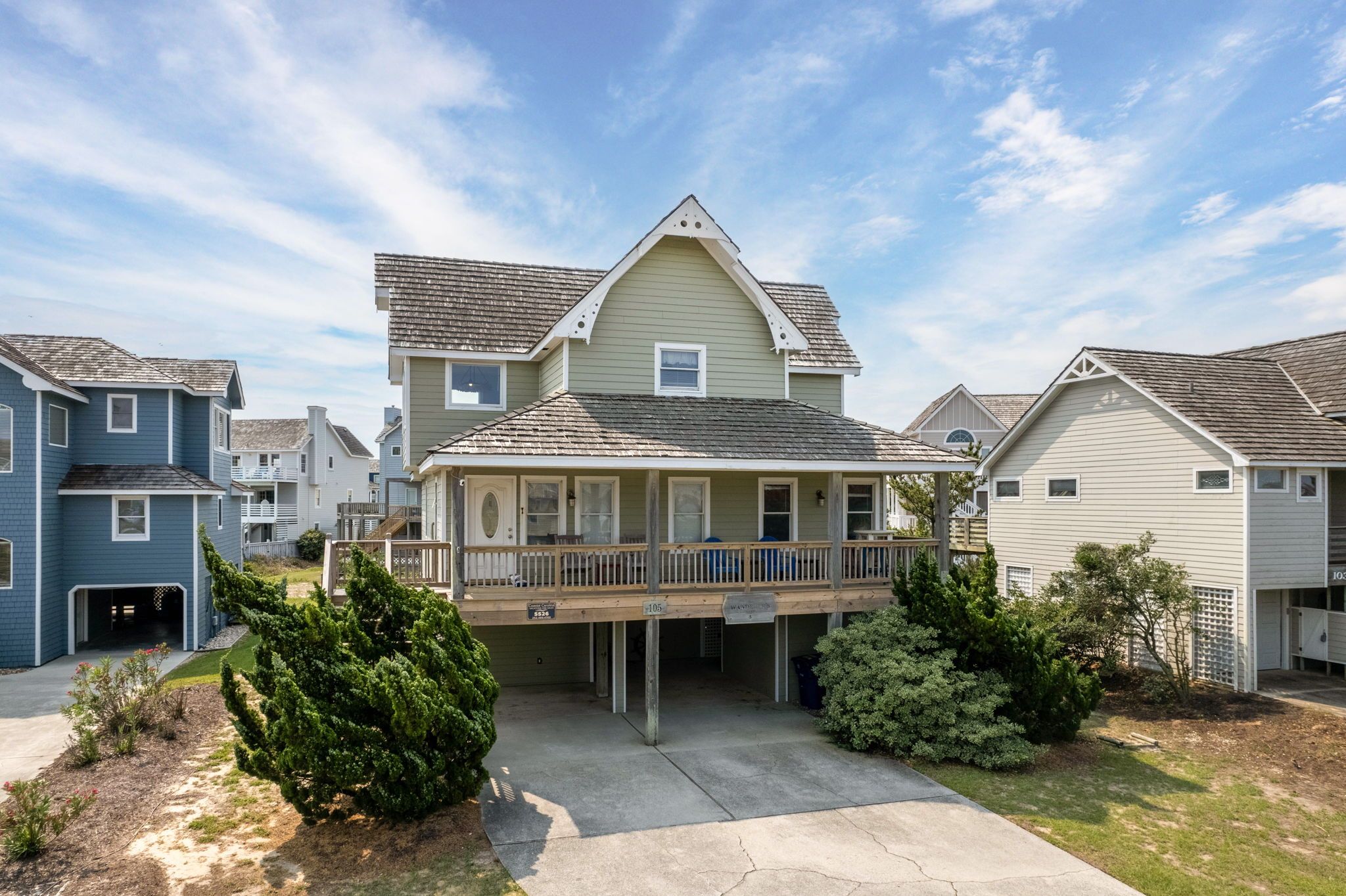 A two-story house with a covered porch, a small garden, and a clear sky.