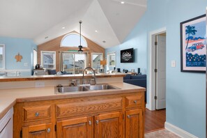 A modern kitchen with a wooden island, built-in cabinets, and a large window. - Wanderer's Rest: Oceanside, Private Pool, Hot Tub, Close to Beach! (Nags Head)