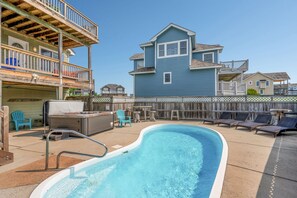 A backyard with a swimming pool, outdoor furniture, and a wooden deck.
