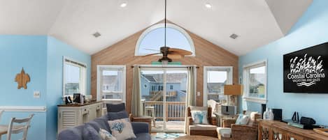 A spacious living area with a large sofa, wicker furniture, and a ceiling fan.