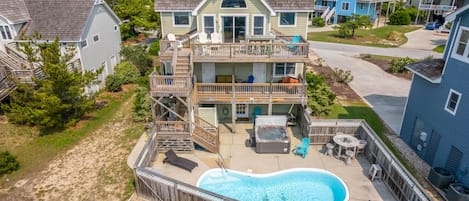 A two-story house with a backyard swimming pool, deck, and outdoor seating area.