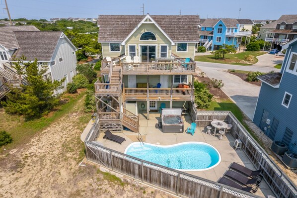 A two-story house with a backyard swimming pool, deck, and outdoor seating area.