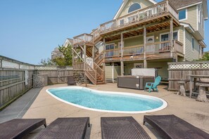 A two-story house with a swimming pool, outdoor furniture, and a wooden deck. - Wanderer's Rest: Oceanside, Private Pool, Hot Tub, Close to Beach! (Nags Head)