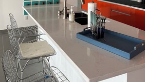 Une cuisine moderne dotée d’un grand îlot central, de luminaires suspendus, d’un pare-feu en marbre et d’un mur entièrement dédié aux chaussures.