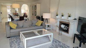 A modern living room with a grey sofa, a glass coffee table, a fireplace, and a television. - Splendid duplex apartment in Estepona (Estepona)