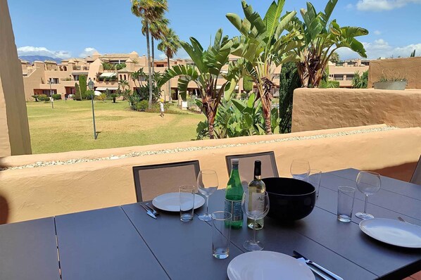 A table set for dining with a view of a resort and palm trees. - Splendid duplex apartment in Estepona (Estepona)