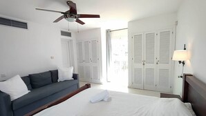 A hotel room with a bed, a gray sofa, a ceiling fan, and white doors. - Splendid duplex apartment in Estepona (Estepona)