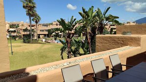 A patio area with a table and chairs, surrounded by a low wall and a pool. - Splendid duplex apartment in Estepona (Estepona)