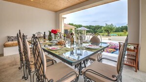 A dining table with chairs, a glass top, and a view of the outdoors.