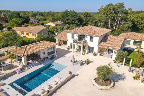 A residential property with a swimming pool, outdoor seating, and a garden.