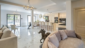 Amplia sala de estar con un sofá grande, una mesa de comedor con sillas, una zona de cocina y una estatua decorativa de un caballo.