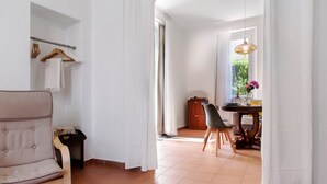Una habitación con una silla, una mesa, un armario y una ventana con cortinas.