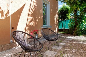 Un espace extérieur aménagé avec deux chaises, une table et un pot de fleurs.