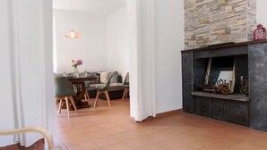 Una sala de estar con chimenea, un comedor con mesa y sillas, y un sofá.