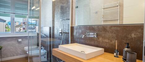 A modern bathroom with a glass shower enclosure, a wooden vanity, and a large mirror.