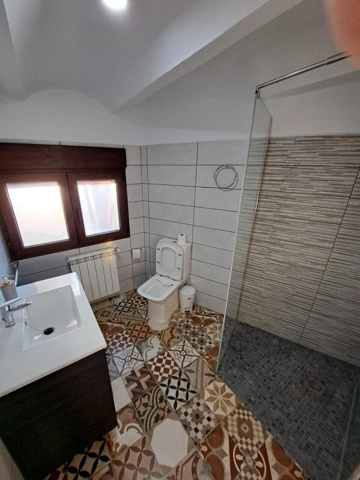 Un baño con inodoro, lavamanos y zona de ducha.