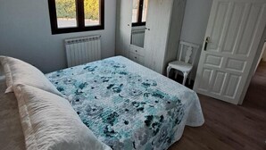 Et soveværelse med seng, vindue, radiator, skab og dør.