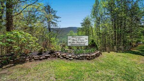Señal de bienvenida en Deer Ridge, con vista a un bosque y colinas al fondo.