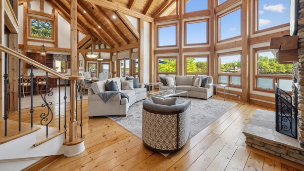 A spacious living area with wooden beams, large windows, and a stone fireplace. - Landing At The Lake: Craftsman Style Home w Pool, Hot Tub (Denver)