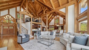 A spacious living area with wooden beams, a staircase, and large windows. - Landing At The Lake: Craftsman Style Home w Pool, Hot Tub (Denver)