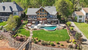 A large house with a swimming pool, a patio, and a well-maintained lawn. - Landing At The Lake: Craftsman Style Home w Pool, Hot Tub (Denver)