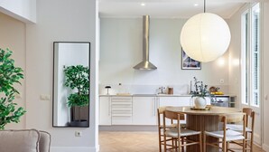 A modern kitchen with a central island, wooden chairs, and a hanging light fixture. - Amazing views over Sagrada Familia (Barcelona)