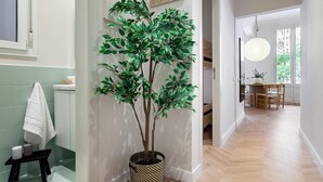 A hallway with a potted tree, a small stool with candles, and a dining area with a table and chairs. - Amazing views over Sagrada Familia (Barcelona)