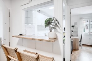 A modern kitchen with white cabinets, a wooden countertop, and a potted plant.