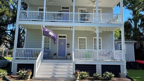 A two-story house with a balcony, a front door, and a small porch area. - 1874 House. Walk Everywhere. Pets Welcome. (Beaufort)