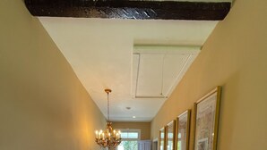 A hallway with wooden flooring, a chandelier, framed pictures on the walls, and a door leading to a balcony. - 1874 House. Walk Everywhere. Pets Welcome. (Beaufort)