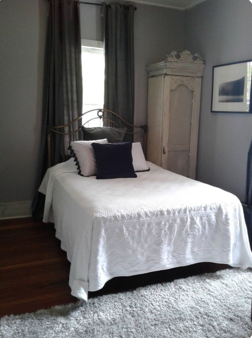 Een slaapkamer met een bed, een kledingkast en een lijst met een afbeelding aan de muur.