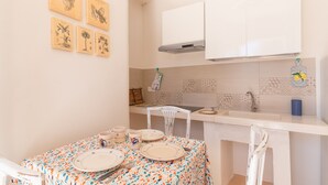 A kitchen with white cabinets, a tiled backsplash, and a dining table set with plates and cutlery.